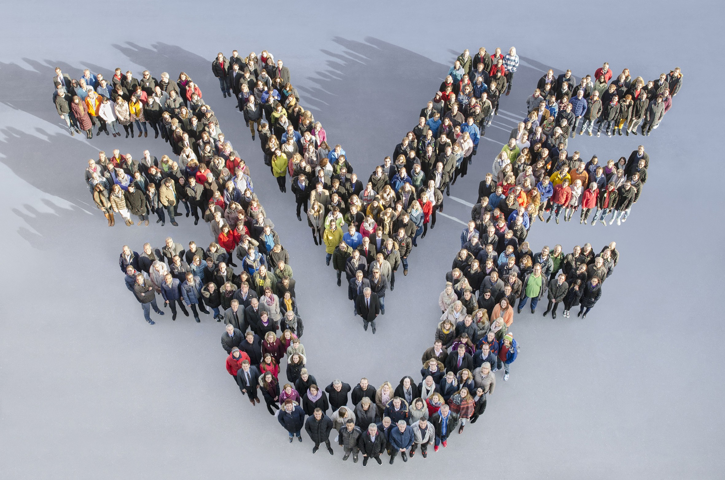 Personen fotografiert von oben, die im Form des uniVersa Bildlogos stehen. Symbol für erneute Auszeichnung als ‚Leading Employer‘