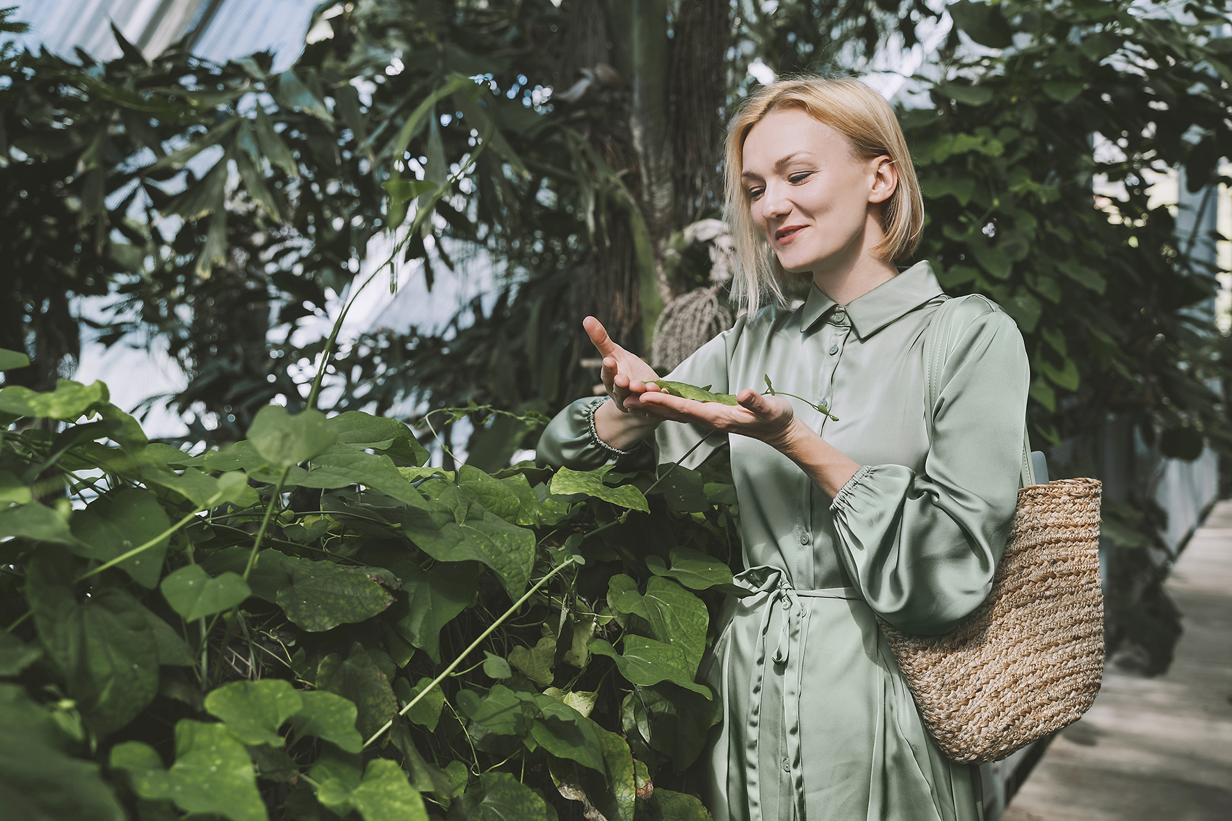 Dame steht im Grünen, hält vorsichtig ein Blatt in Händen. Symbol für nachhaltige Versicherung topgreeninvest der uniVersa