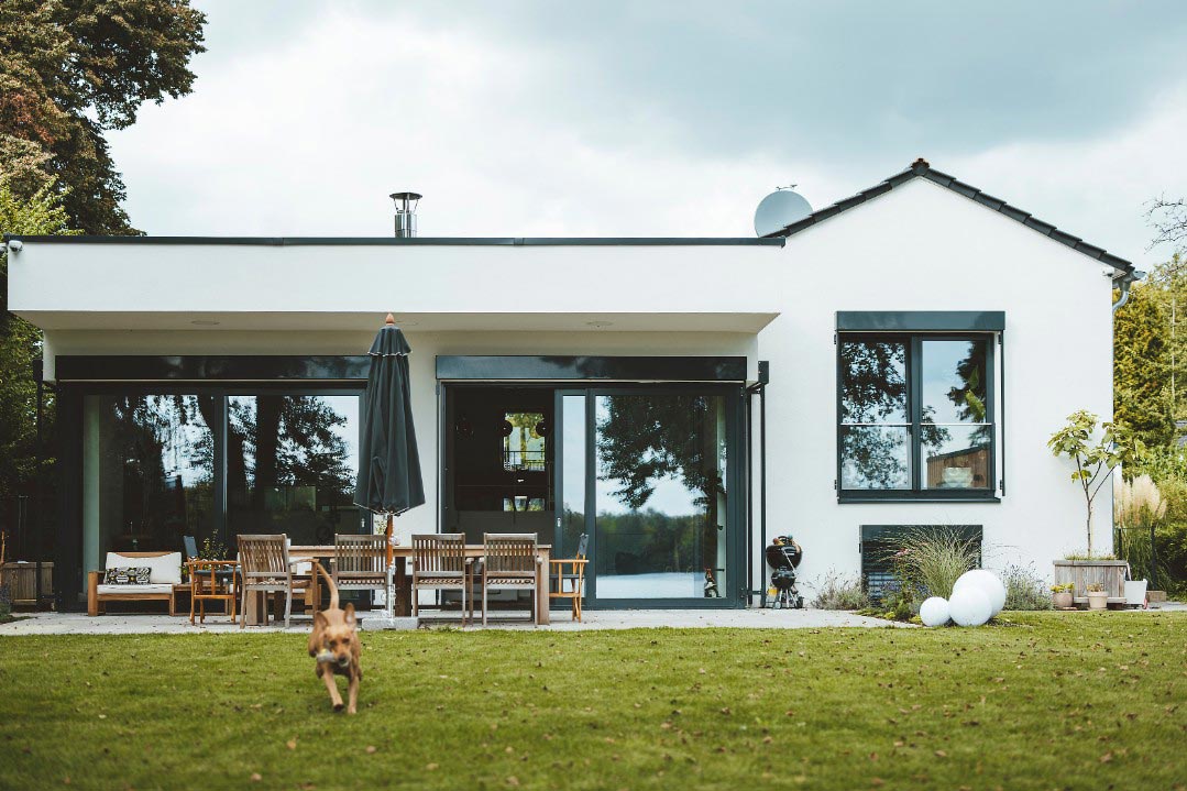 Blick vom Garten auf modernes Einfamilienhaus. Symbol für Tipp ' Wie versichere ich meine Balkon-Solaranlage'