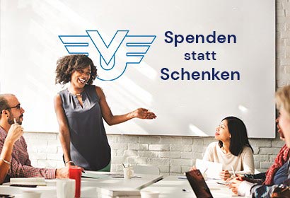 Personen im Meetingraum. Auf Projektionswand ist das UniVersa Logo abgebildet und der Text ‚Spenden statt schenken‘